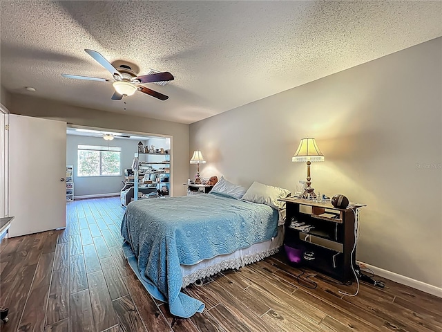 bedroom with baseboards, a textured ceiling, ceiling fan, and wood finished floors