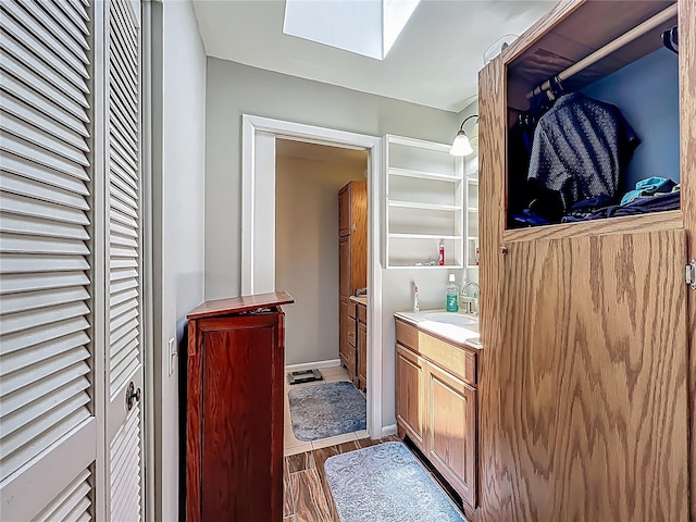 bathroom featuring a skylight, vanity, a closet, and wood finished floors