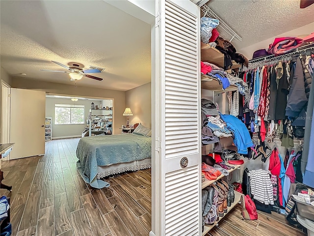 bedroom with a ceiling fan, a textured ceiling, and wood finished floors