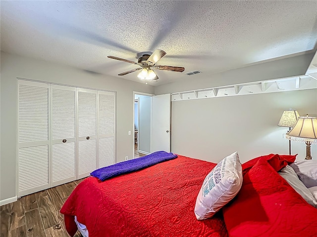 bedroom with visible vents, a ceiling fan, a textured ceiling, and wood finished floors