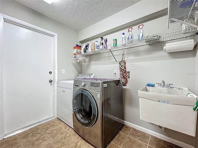 washroom with washing machine and clothes dryer, a textured ceiling, laundry area, and a sink