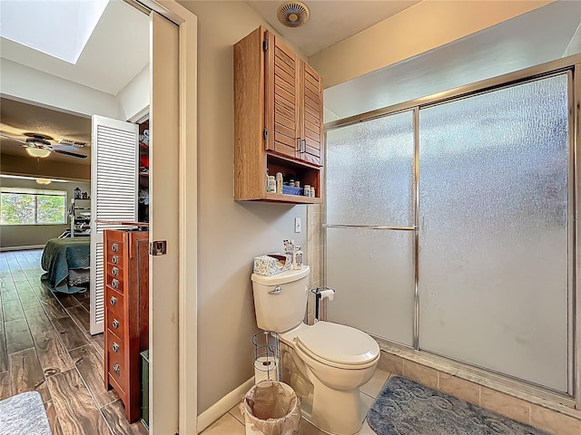 3932 Watson Dr, New Port Richey, FL 34655 - full bath featuring an enclosed shower, toilet, wood finished floors, a skylight, and baseboards