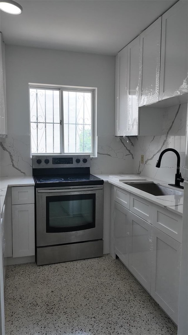 2921 SW 10th St Unit 23, Miami, FL 33135 - kitchen featuring stainless steel range with electric stovetop, backsplash, white cabinetry, and dark speckled floor