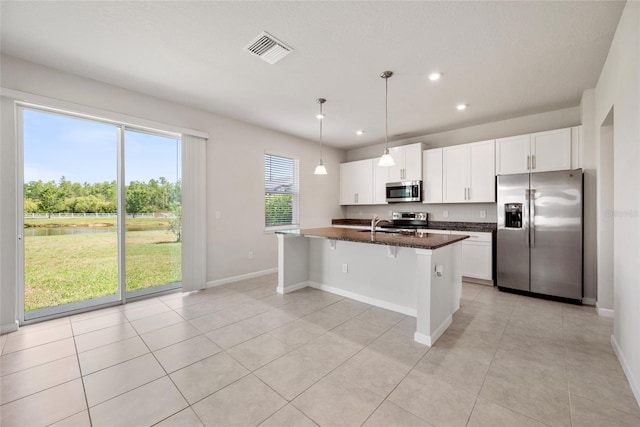 8595 Prairie Creek Dr, New Port Richey, FL 34655 - kitchen featuring appliances with stainless steel finishes, recessed lighting, a breakfast bar, white cabinets, and a kitchen island with sink