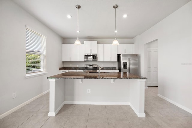 8595 Prairie Creek Dr, New Port Richey, FL 34655 - kitchen featuring appliances with stainless steel finishes, a kitchen island with sink, dark stone countertops, a sink, and white cabinets