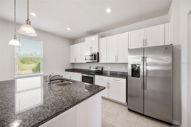 8595 Prairie Creek Dr, New Port Richey, FL 34655 - kitchen with stainless steel appliances, a sink, white cabinets, dark stone counters, and decorative light fixtures