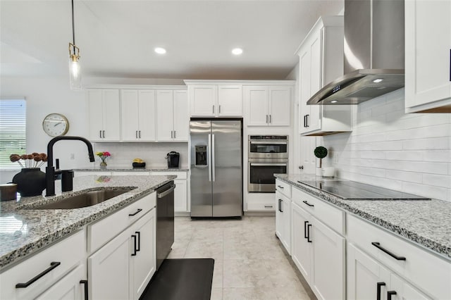 kitchen featuring stainless steel appliances, wall chimney exhaust hood, a sink, decorative backsplash, and white cabinets