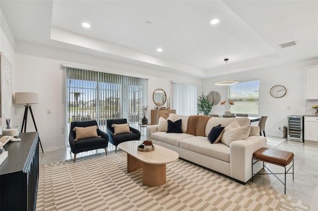 living room with a raised ceiling, wine cooler, light tile patterned floors, and recessed lighting