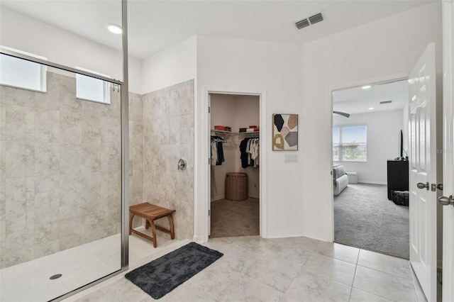 ensuite bathroom featuring a walk in shower, a spacious closet, tile patterned floors, and recessed lighting
