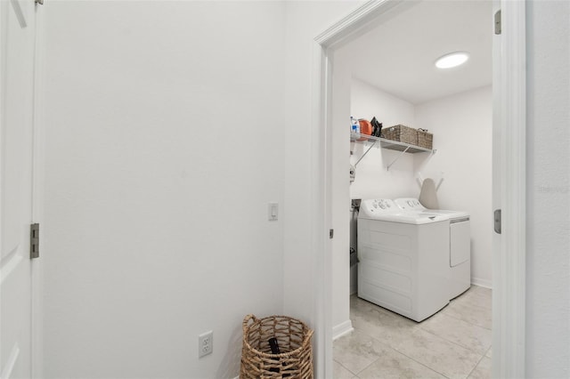 laundry area with light tile patterned floors, washer and clothes dryer, and baseboards