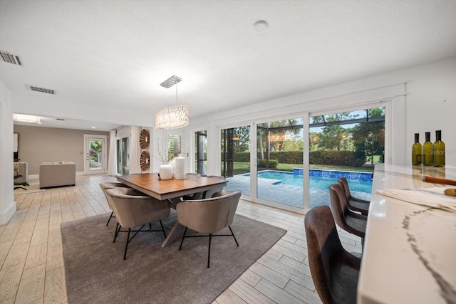 dining space with visible vents, plenty of natural light, an inviting chandelier, and light wood-type flooring
