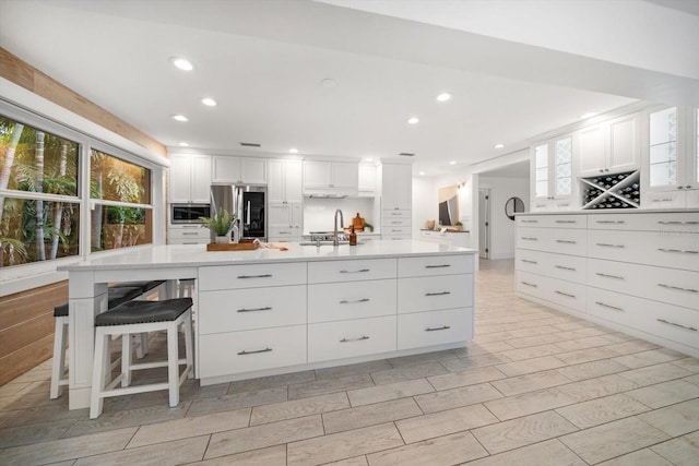 kitchen featuring a healthy amount of sunlight, appliances with stainless steel finishes, light countertops, recessed lighting, and white cabinetry