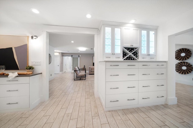 interior space featuring baseboards, light wood finished floors, and a barn door