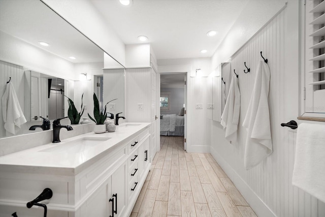 ensuite bathroom with a sink, ensuite bathroom, double vanity, and wood finished floors