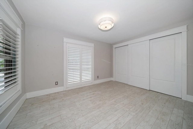 unfurnished bedroom with baseboards, a closet, and light wood-type flooring