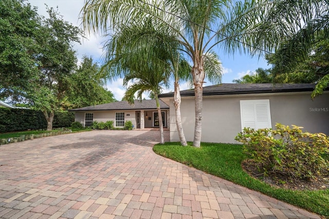 ranch-style house featuring stucco siding and decorative driveway