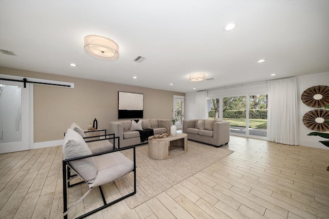 living room featuring light wood-style floors, recessed lighting, a barn door, and visible vents