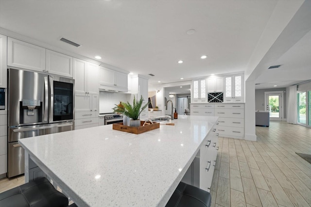 kitchen featuring stainless steel appliances, visible vents, white cabinetry, and a sink