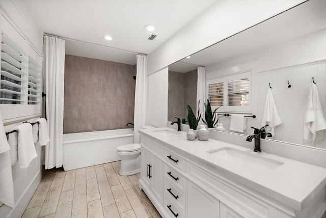 full bathroom with visible vents, a sink, wood finished floors, and toilet