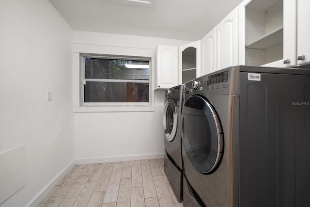clothes washing area with separate washer and dryer, light wood-style floors, cabinet space, and baseboards
