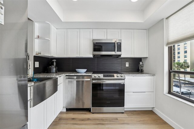 kitchen with open shelves, white cabinets, appliances with stainless steel finishes, and a tray ceiling
