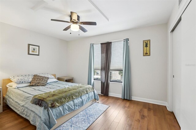 bedroom featuring baseboards, a ceiling fan, wood finished floors, and a closet