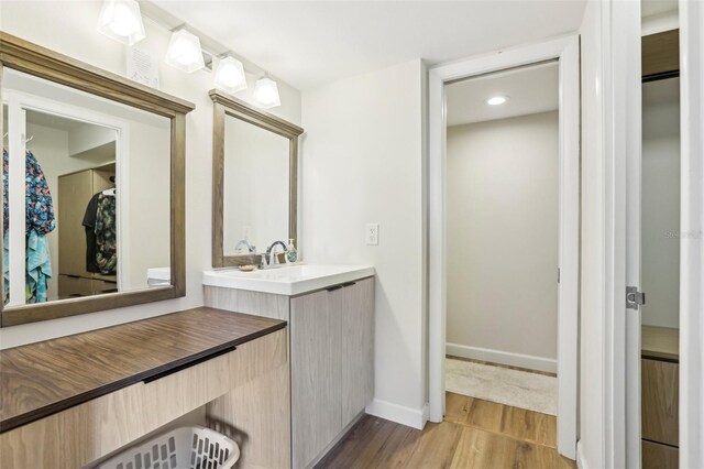 bathroom with baseboards, wood finished floors, and vanity