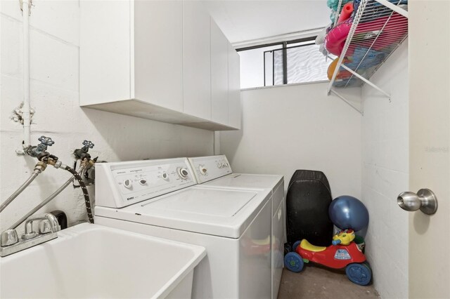 clothes washing area featuring a sink, cabinet space, and washer and clothes dryer