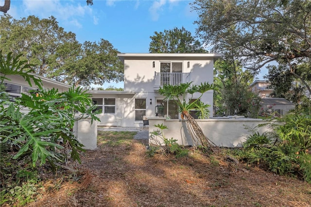 back of property featuring a balcony and stucco siding