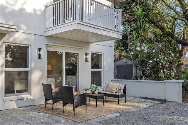 view of patio / terrace with a balcony, a storage shed, an outbuilding, and an outdoor living space