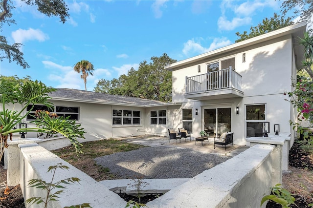 back of house with a balcony, an outdoor living space, a patio area, and stucco siding