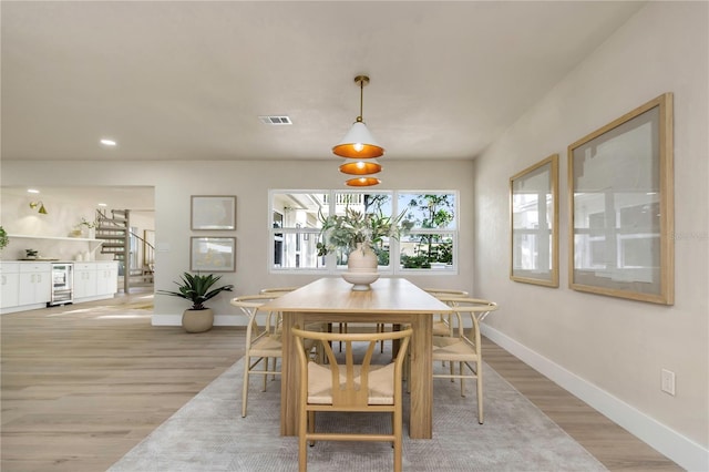 dining space featuring beverage cooler, light wood-style flooring, baseboards, stairs, and recessed lighting