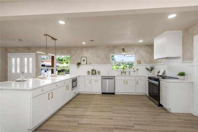 kitchen with stainless steel appliances, a peninsula, a sink, recessed lighting, and light wood-type flooring
