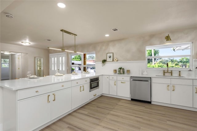 kitchen with stainless steel appliances, a sink, a peninsula, open shelves, and light countertops