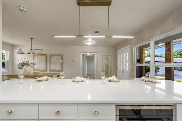 kitchen with white cabinetry, light countertops, and black oven
