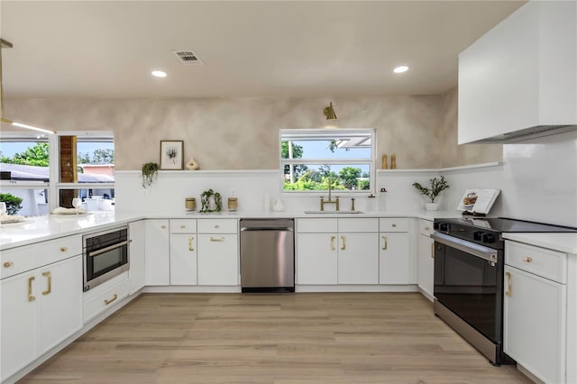 kitchen featuring stainless steel appliances, open shelves, a sink, white cabinetry, and light countertops