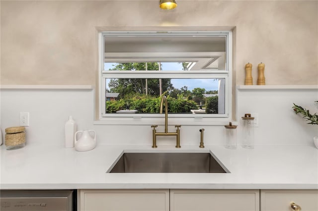 kitchen with a sink, dishwasher, light countertops, and white cabinets