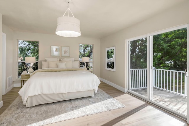 bedroom featuring access to outside, light wood-type flooring, and baseboards