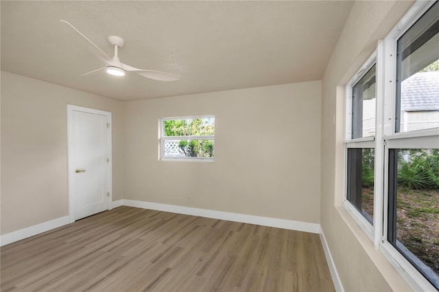 empty room with light wood-style flooring, a ceiling fan, and baseboards