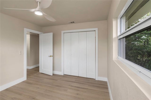 unfurnished bedroom featuring baseboards, light wood-style flooring, a ceiling fan, and a closet