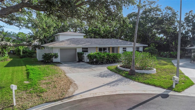 single story home with an attached garage, a front lawn, concrete driveway, and stucco siding