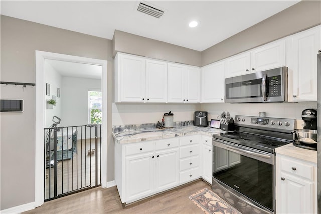 607 Carolyn Dr, Brandon, FL 33510 - kitchen with visible vents, light wood-type flooring, light countertops, white cabinetry, and stainless steel appliances