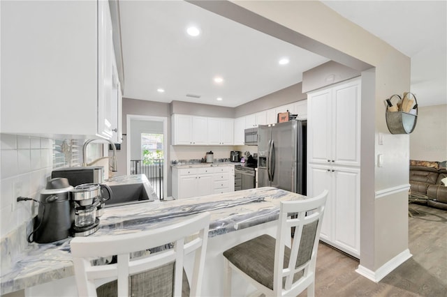 607 Carolyn Dr, Brandon, FL 33510 - kitchen featuring white cabinets, a peninsula, stainless steel appliances, recessed lighting, and light wood-style flooring