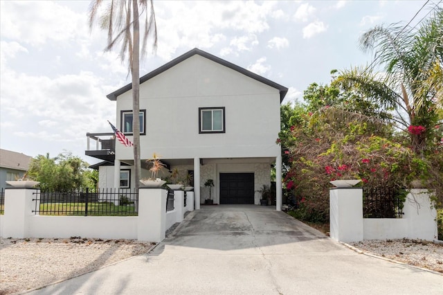 exterior space with a garage, a fenced front yard, driveway, and a balcony