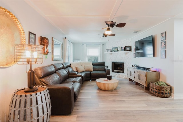 living room with ceiling fan, visible vents, wood finished floors, and a fireplace