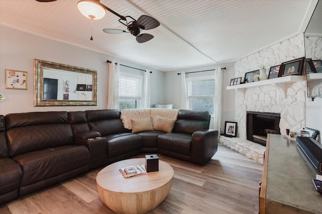 living room featuring a ceiling fan, light wood-style flooring, and a fireplace