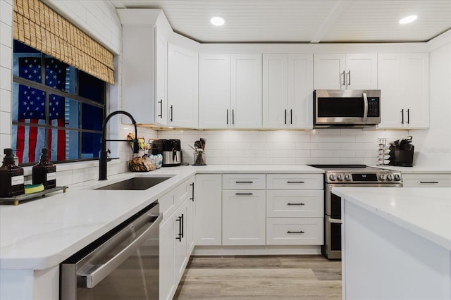 kitchen with recessed lighting, appliances with stainless steel finishes, a sink, and light wood-style flooring