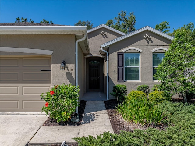 doorway to property featuring an attached garage and stucco siding