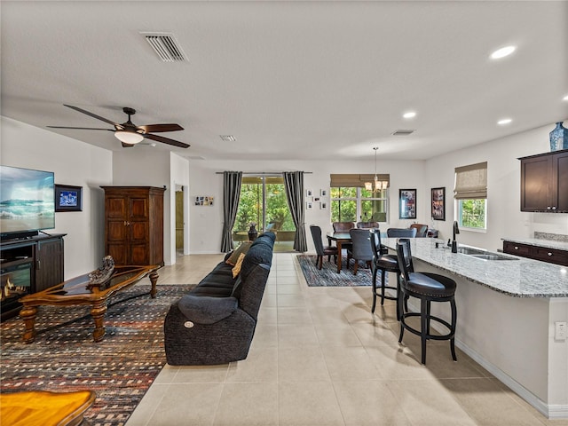 living room with recessed lighting, visible vents, light tile patterned flooring, and ceiling fan with notable chandelier