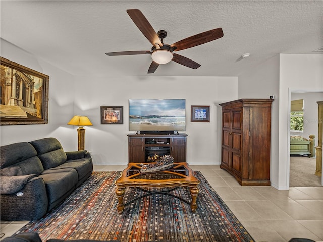 living area featuring ceiling fan, light tile patterned flooring, a textured ceiling, and baseboards